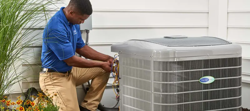 HVAC technician cleaning condenser coils on an outdoor AC unit in Orlando, FL